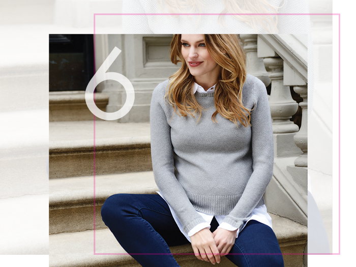 Blonde pregnant model sits on some steps wearing a grey Seraphine jumper.