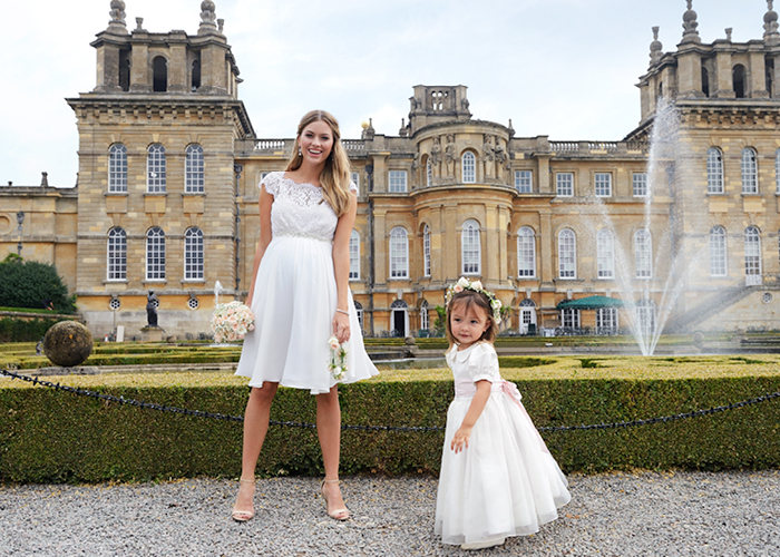 Bride wearing a short wedding dress with flower girl outside Blenheim Palace