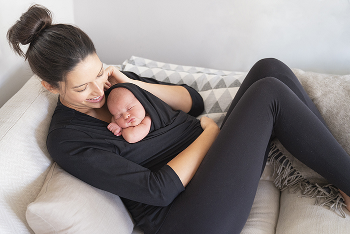 New mother wears her newborn in the Seraphine Skin to skin top