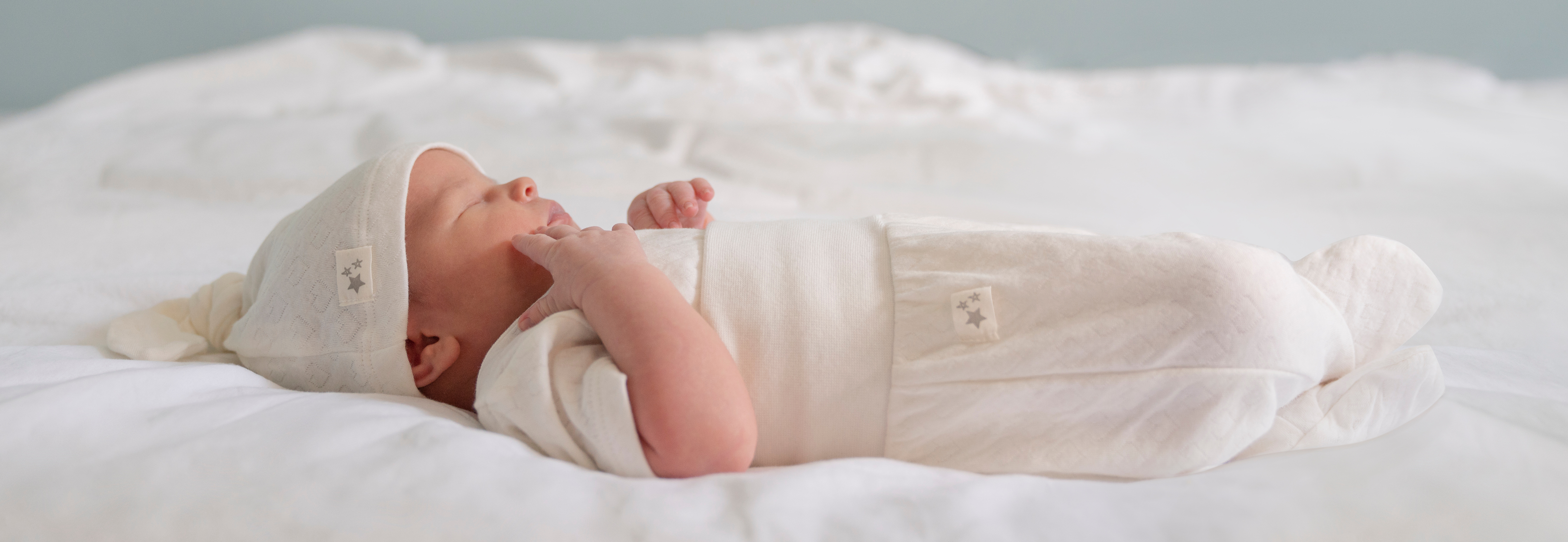 Newborn baby wears Seraphine organic baby clothes
