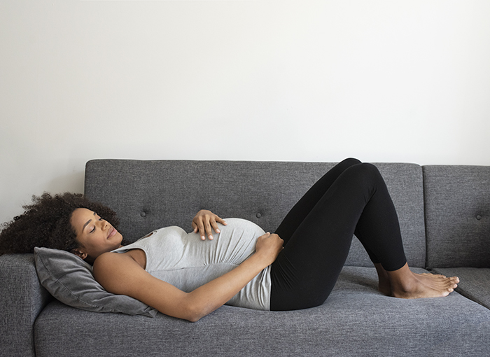 Pregnant woman wearing maternity leggings & a tank top. Must-haves for the hospital bag